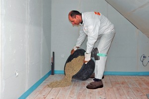  Die im Eimer mit Wasser angemischte gebundene Schüttung wird auf den Rohboden gekippt und damit der erste der beiden Dämme ausgebildet 