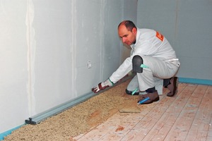  Die im Eimer mit Wasser angemischte gebundene Schüttung wird auf den Rohboden gekippt und damit der erste der beiden Dämme ausgebildet 