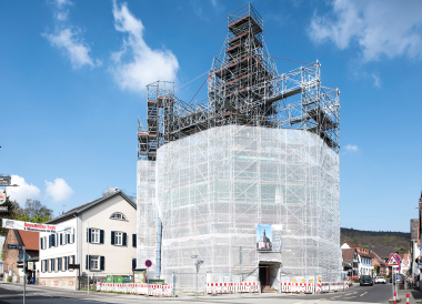 Allround-Fachwerkträger als freitragende Überbrückungen für die Einrüstung des zentral aufgesetzten Glockenturms der evangelischen Kirche in Wiesbaden Naurod Foto: Layher