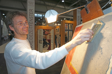 Ulrich Bettentrup zeigt auf dem Stand der Firma Kreidezeit den Putzauftrag für die Herstellung von Stuccolustro