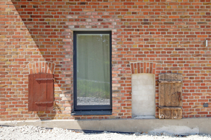  Neu ins Mauerwerk geschnittene Fensteröffnung. Links und rechts davon alte Öffnungen, die zugemauert wurden ? mit den originalen Stalltüren davor 