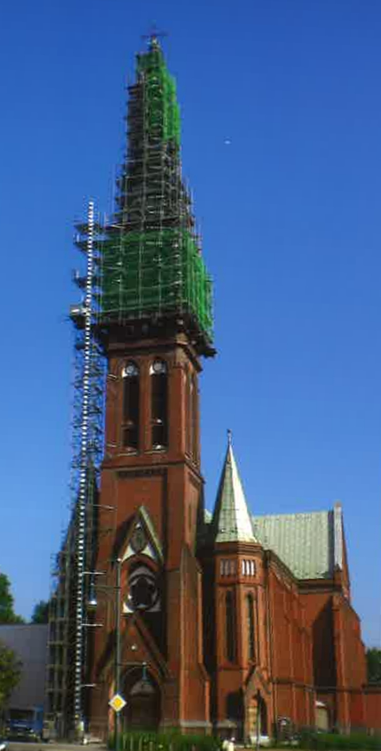 Kirchturm, 83 m Höhe, mit eingerüstetem Turmaufsatz und kombiniertem Material-und Personenaufzug. Das Gerüst ruht auf einem im obersten Turmgeschoss eingezogenen Trägerrost. Die Mitwirkung eines Hochbaustatikers und des Statikers einer Gerüstbaufirma sowi