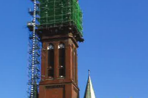  Kirchturm, 83 m Höhe, mit eingerüstetem Turmaufsatz und kombiniertem Material-und Personenaufzug. Das Gerüst ruht auf einem im obersten Turmgeschoss eingezogenen Trägerrost. Die Mitwirkung eines Hochbaustatikers und des Statikers einer Gerüstbaufirma sowi 