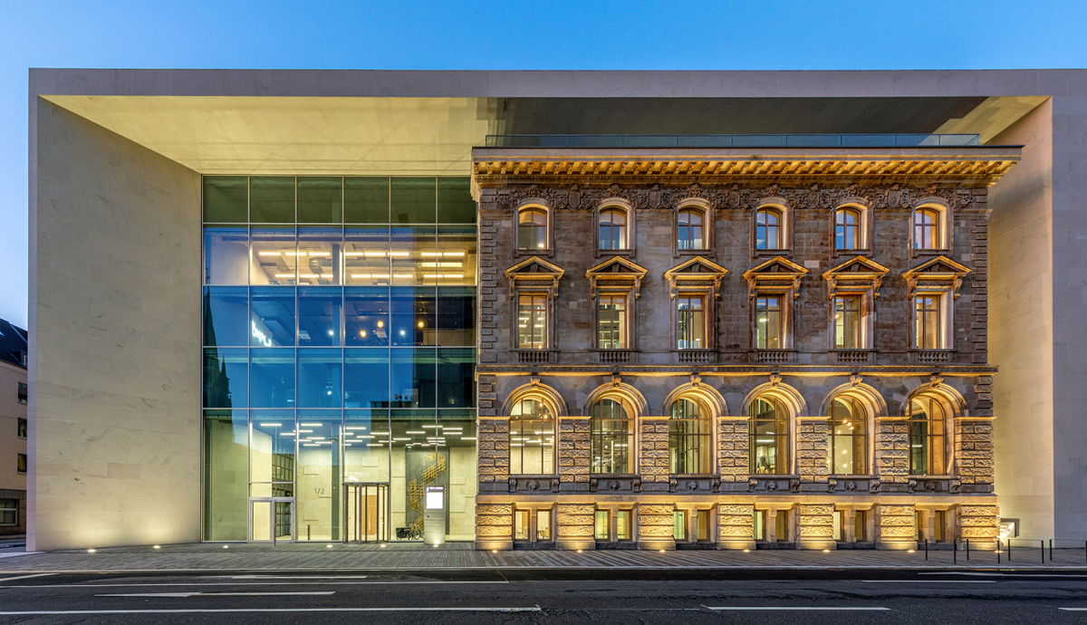 Die neoklassizistische Bestandsfassade wird vom Neubau mit seiner Glas- und Sandsteinfassade eingerahmt