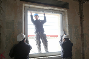  Mit vereinten Kräften werden die großen Fensterrahmen in die offene Laibung eingesetzt 