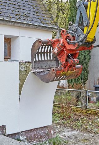 Die Putzstreifen werden ähnlich wie eine Tapete mit dem Greifer eines Baggers vom Dämmstoff abgezogen