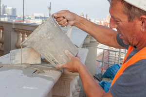  Die größeren Sandsteine der Balustrade wurden auf die gleiche Weise mit Mörtel verfüllt wie die Sandsteine der Fassade. Mit einem Messbecher gelangt der hochfließfähige Trass-Kalk-Mörtel in die Fugen    