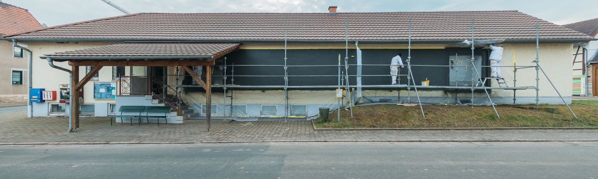 Auf der Straßenseite erhielt die Fassade des ehemaligen Konsum-Marktes in Sundhausen eine anthrazitfarbene Putzfläche als Untergrund für den späteren Schriftzug „Sundhausen“