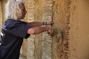  Anwendungstechnikerin Anja Bargel-Schütte zeigt, wie der Lehm mit der Kelle an die Wand geworfen wird. 