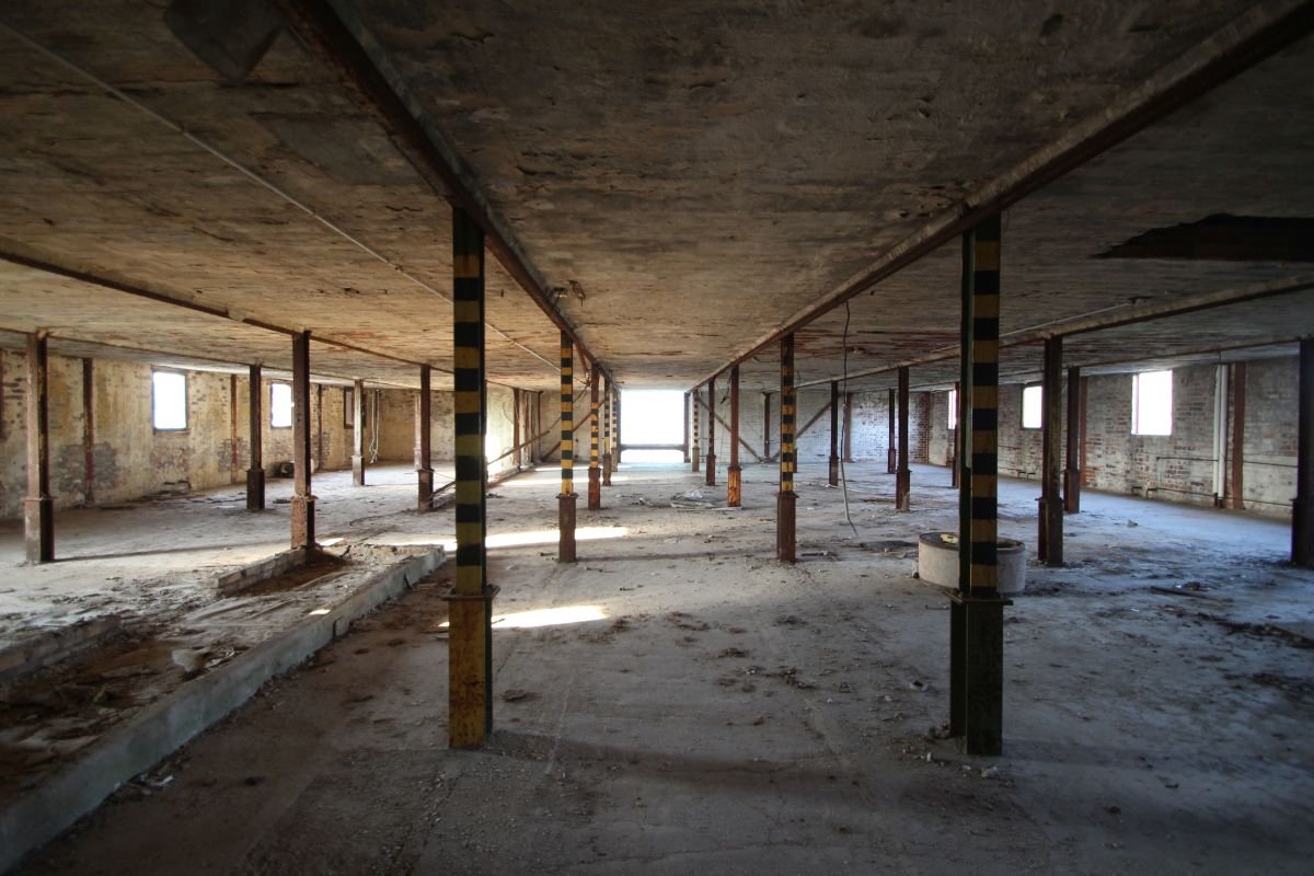 Die Neufert-Hallen in Weißwasser sind zurzeit noch unsaniert – ein Lost Place mit von Stahlstützen und verputzen Backsteinwänden abblätternder Farbe
