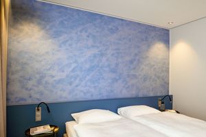  In wolkigem Blau individuell gestaltete Fläche einer Kopfwand in einem der Gästezimmer im B-Wohnen von Brillux in Münster 