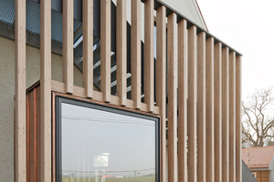  Von außen wird das Fenster an der Westseite von einer an die Holzkonstruktion im Inneren erinnernde Lamellenwand eingerahmt 