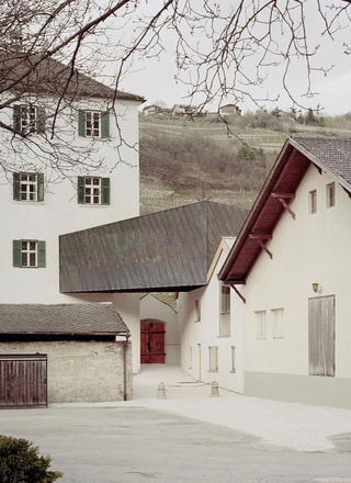 Die Brücke führt in das Obergeschoss des Bestandsgebäudes. Von außen ist sie mit schwarz oxidiertem Kupferbleche bekleidet