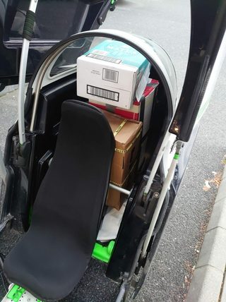 Der „Kofferraum“ hinter dem Fahrersitz bietet mit 160 Litern Platz für Werkzeug und etwas Material beziehungsweise, wie hier zu sehen, für ein paar Pakete. Größere Gegenstände können per Anhänger mitgenommen werden