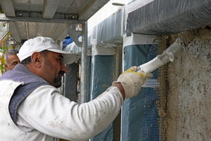  Der Handwerker beginnt die Putzapplikation auf der zurückgebauten Wandfläche 