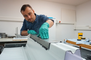  Florian Ilg, wissenschaftlicher Mitarbeiter im Institut für Material- und Bauforschung, bringt eine klebtechnische Verstärkung auf einem Modell der Deckenunterseite eines Parkhauses auf  