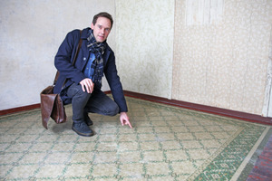  LWL-Denkmalpfleger Marcus Brokmann zeigt einen alten Linoleum-Boden aus der Zeit, als die Baracke als Flüchtlings-Wohnungen genutzt worden war 