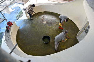 Die Betonoberfläche der Terrasse vor dem Eingang wurde mit Besen gesäubert, um die obersten 2 mm des Zementsteins zu lösen und somit das Korngerüst des Zuschlags (Gesteinskörnung mit maximalem Durchmesser von 2 mm) freizulegen.  Dadurch bekommt die Oberfl