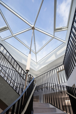 In der Gebäudemitte liegt das Treppenhaus, das durch die Glasüberdachung mit Tageslicht versorgt wird