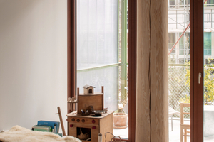  Die geschälten Fichtenstämme sind über Fuß- und Kopfplatten mit den Deckenplatten vergossen. Hinter der Fassade ist die Stahlkonstruktion der Balkone zu sehen 