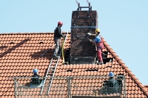  Unter den wachsamen Augen der Bauaufsicht wird die Hebevorrichtung am alten Schornstein befestigt 