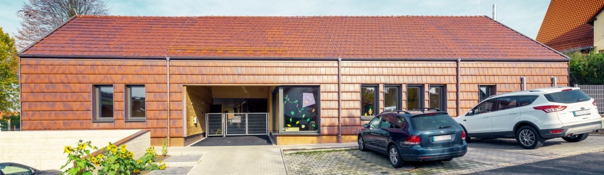 Kindergarten in Motten: Außen Ziegelfassade und innen transparent lasiertes Holz und versiegelter Sichtbeton