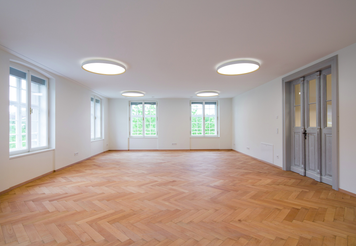 Der Aufenthaltsraum im zweiten Obergeschoss des Osttrakts mit revitalisiertem, historischen Fischgrätparkett und Holzfenstern