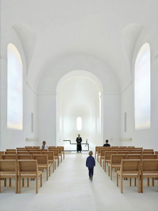 Heute ist der Kirchraum hell und licht, der Chorraum ist geöffnet und Altar und Bestuhlung sind gestalterisch reduziert