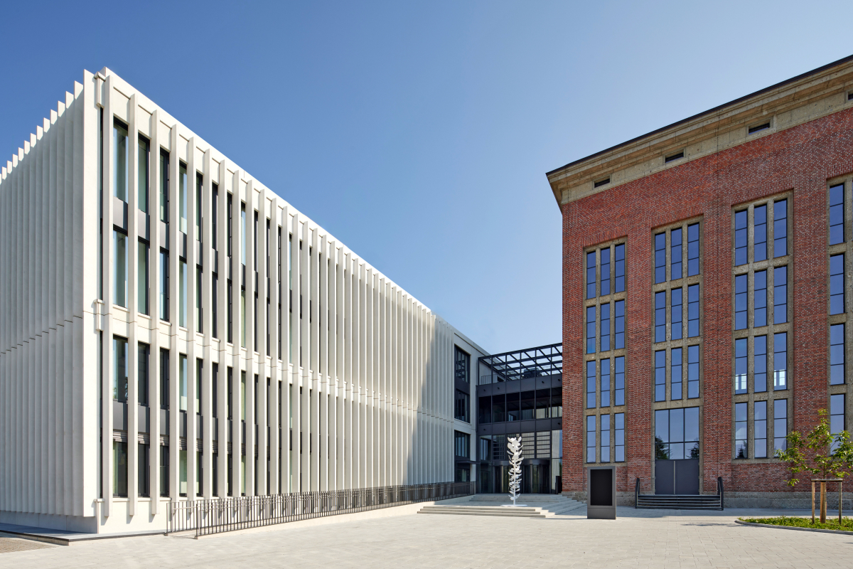 Neben dem sanierten Bestandsbau (reche Seite) ergänzten die Architekten einen Neubau mit weiß eingefärbten Fertigteillamellen an der Fassade