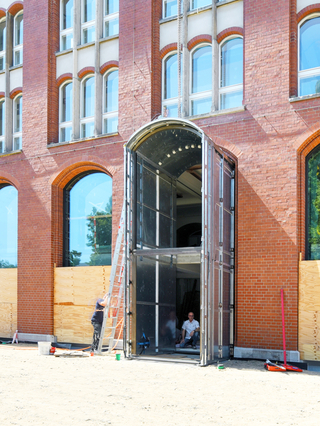 Die gebogene Metallunterkonstruktion für das Portal des neuen Haupteingangs steht bereits. Jetzt muss noch die Wandung aus brüniertem Messingblech (Baubronze) aufgebracht werden
