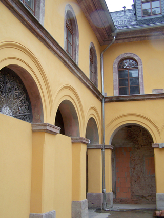 Die farbliche Fassung in gelb-ocker in Kombination mit Porphy-relementen unterstützt den architektonischen Gesamteindruck des Innenhofs