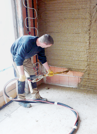 Der Lehmgrundputz wird mit der Putzmaschine auf die Ziegelwände aufgebracht