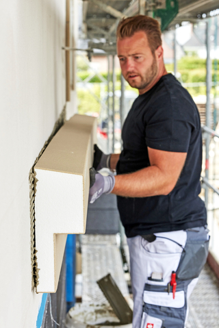 Das vorgefertigte Fassadenprofil setzen Handwerke-rinnen und Handwerker in den frischen Klebemörtel ein und richten es exakt aus