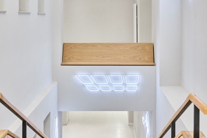  Zwischen der Ostfassade des Kernbaus und dem Atrium verbindet eine einläufige Treppe das erste mit dem zweiten Obergeschoss (Lichtinstallation: Patricia Pisani) 