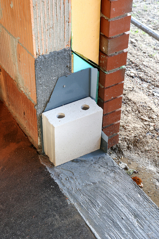 Schutz der Fensterecke während der Bauphase mit einem Stein