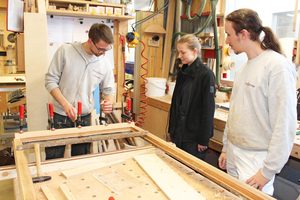  Lejla Lier und Maximilian Kinder absolvieren bei Kramp &amp; Kramp in Lemgo das Freiwillige Handwerksjahr und erleben die Restaurierung von Bauelementen Schritt für Schritt. Hier schauen sie Tischler Noah Prasuhn (links) zu  