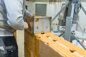  Auftrag des Lehmdünnbettmörtels mit einem Mörtelschlitten mit Torbogen 