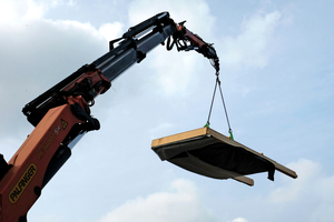  Ein vorgefertigtes Fassadenelement mit Strohdämmung hängt am Kran 