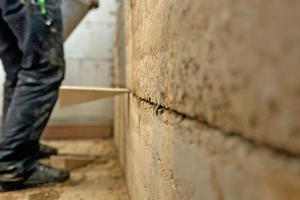  Montage von vorgefertigten Wandelementen, die mit einem Lehmkleber an die Wand gepresst werden 