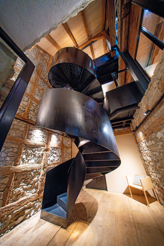 Die Wendeltreppe aus schwarzem Stahl steht wie eine Skulptur in dem zweigeschossigen Raum