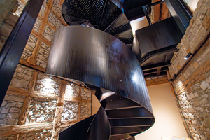  Die Wendeltreppe aus schwarzem Stahl steht wie eine Skulptur in dem zweigeschossigen Raum 