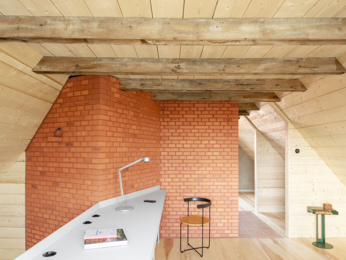 Erschließungskern aus Ziegeln im Obergeschoss und Arbeitsplatz an der Galerie zum Luftraum über dem Erdgeschoss