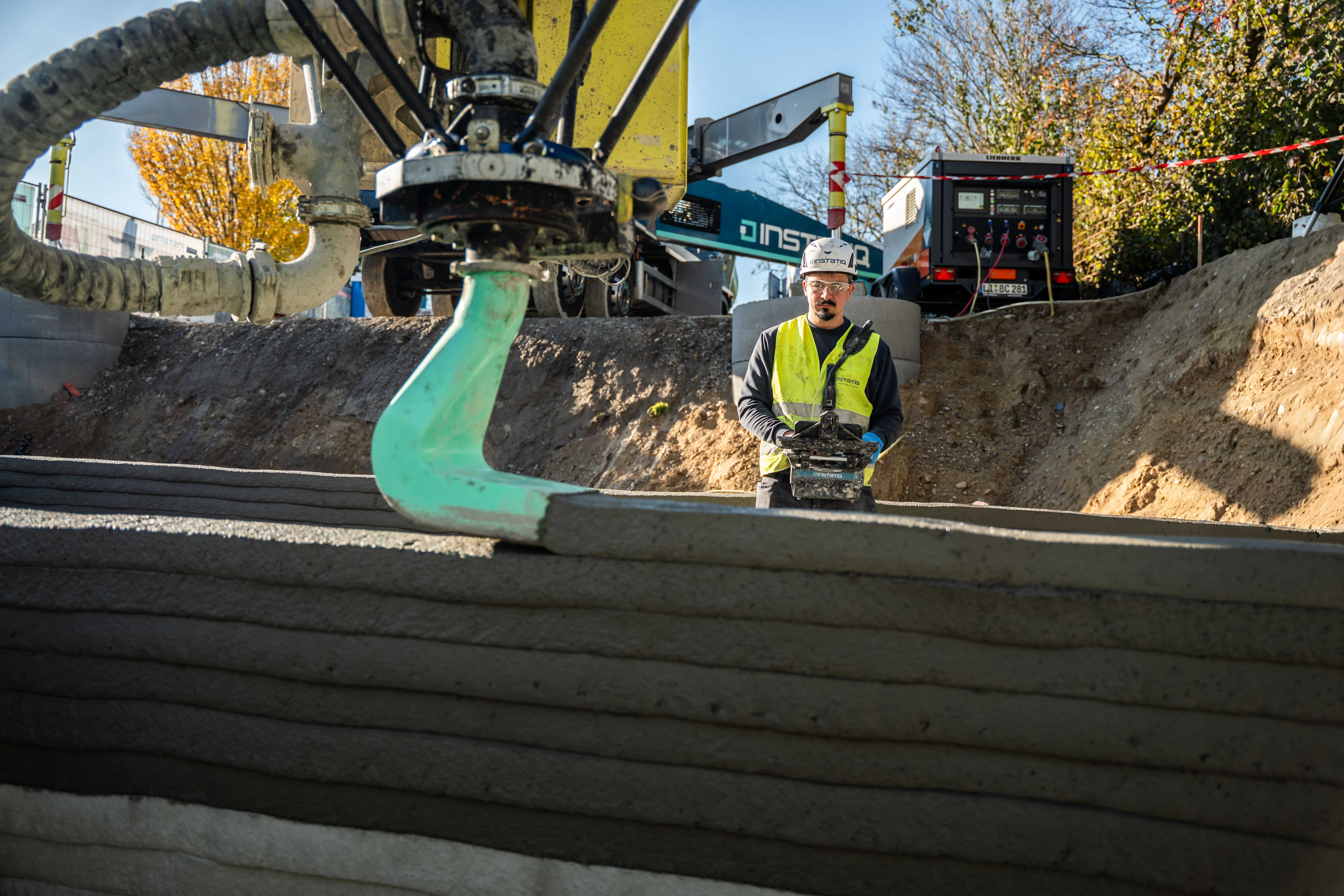 Mit einer Reichweite von bis zu 26 m und einer Druckgeschwindigkeit von bis zu 10 cm pro Sekunde entstehen direkt auf der Baustelle tragende Betonwände Schicht für Schicht