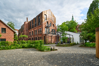 Die Aufstockung scheint aus der Backsteinarchitektur des „Riegels“ herauszuwachsen