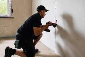  Der Handwerker verschraubt Gipskartonplatten auf der Unterkonstruktion 