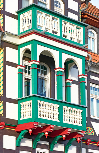 Grüne Akzente betonen den hervorspringenden Balkon am Mittelteil des Fachwerkgebäudes
