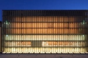  Durch die transluzente Fassade aus heiß verformtem Glas schimmert der Kubus des Lesesaals abends vom inneren Licht 