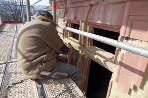  Einer der Steinmetze baut ergänzende Sandsteinteile in die Gewände der Kreuzstockfenster ein 