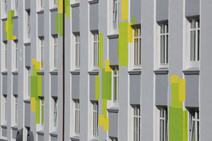  Die straßenseitige Fassade des Wohnblocks zeigt sich in edlen Grautönen, die die Schmuckelemente betonen und fröhlich-aufglockerten Farbflächen 