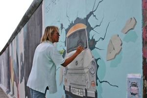  Künsterlin bei der Wiederherstellung des Bildes "Trabi durchbricht die Mauer" 